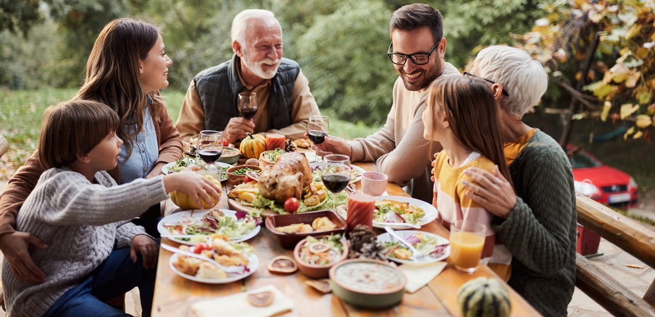 Multigenerational family eating dinner outside.