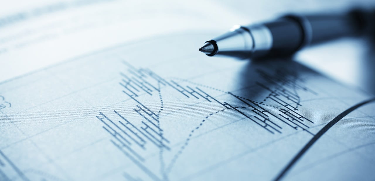 Stock market data on paper with a pen sitting atop the paper