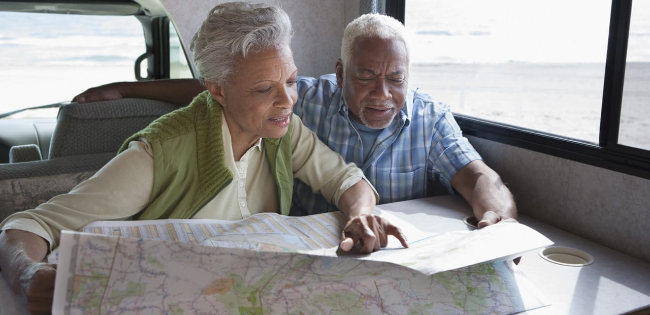 Couple looks at a paper map while sitting at the table in a mobile home