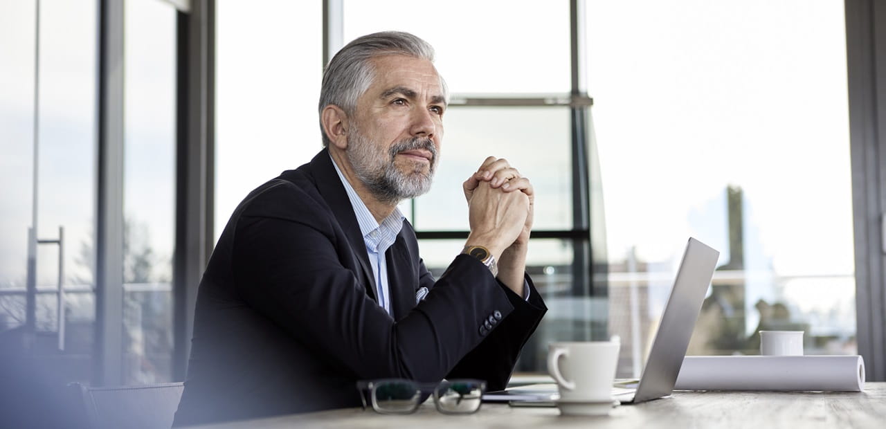 Man sitting in front of his laptop looking off in thought.