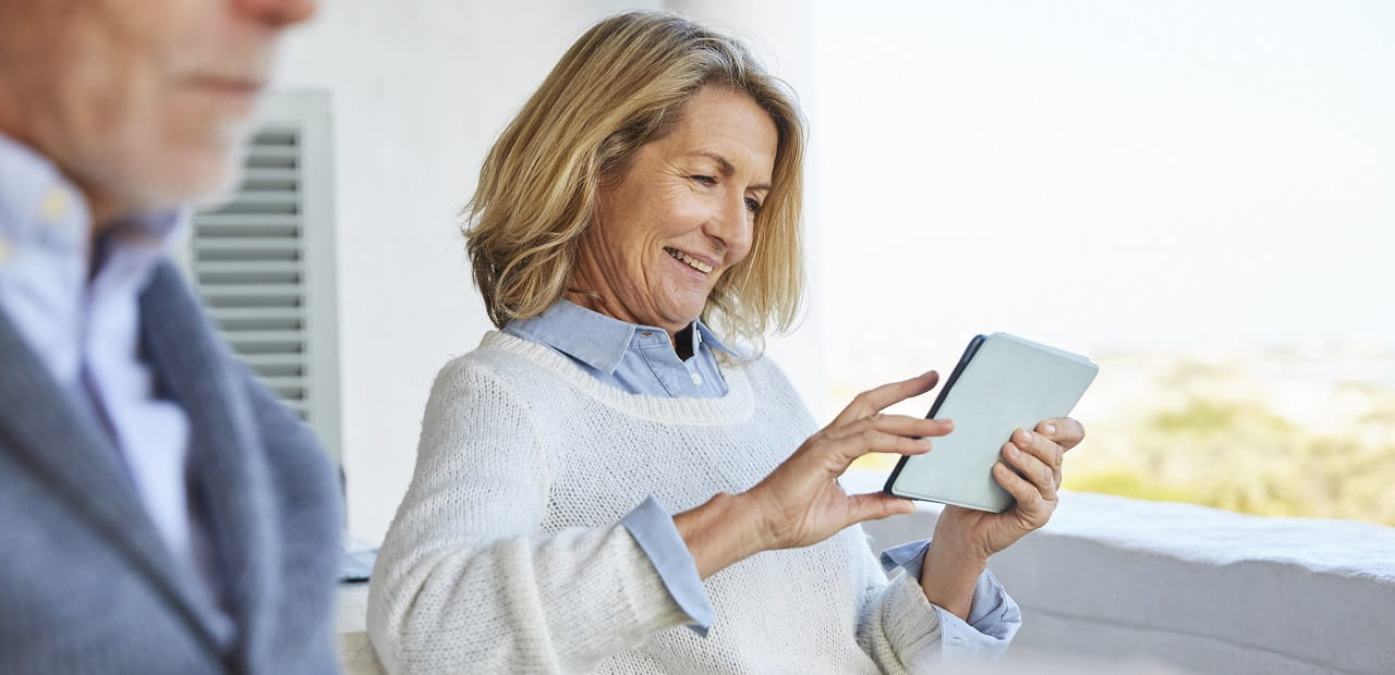 Women looking at a tablet on a porch.